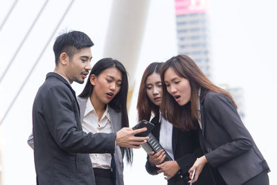 Businessman showing mobile phone to female colleagues