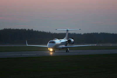 Airplane on runway against sky during sunset