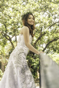 Portrait of smiling woman standing against trees