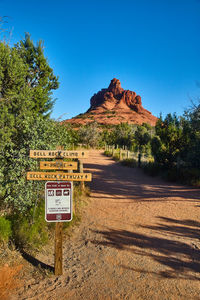 Road sign on field against clear blue sky