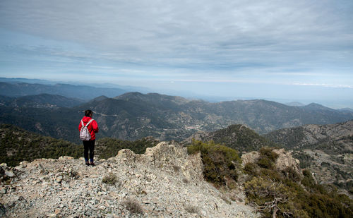 Rear view of man standing on mountain against sky