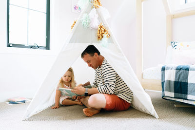 Closeup portrait of a dad and child reading together in a child's room