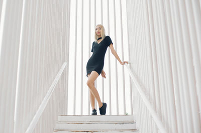 Full length of woman standing on steps amidst railing