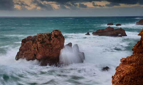 Scenic view of rocks in sea against sky