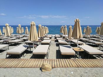 Row of chairs on beach against blue sky