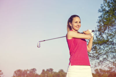 Portrait of smiling young woman standing against sky