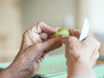 Cropped image of woman cutting brussels sprout at home