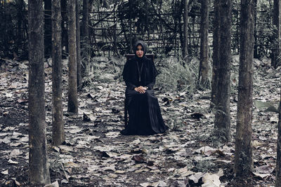 Full length portrait of woman sitting in forest