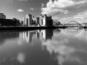 Bridge over river by buildings against sky