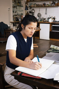 Businesswoman writing in diary while working at home office