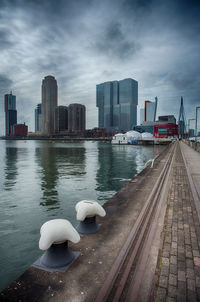 City at waterfront against cloudy sky