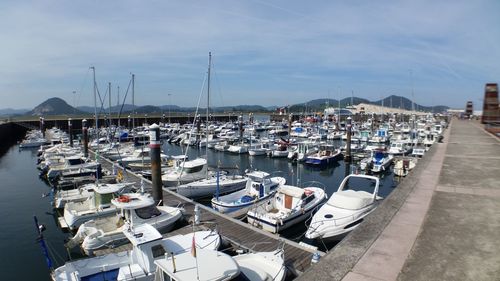 Boats moored at harbor against sky