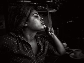 Close-up of thoughtful young woman looking away while sitting on chair at night