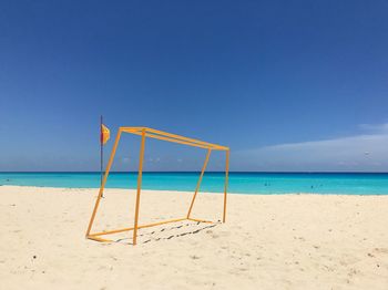 Lifeguard hut on beach against clear blue sky