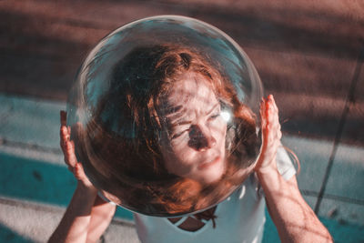 Close-up high angle view of thoughtful young woman wearing glass helmet in head during sunny day