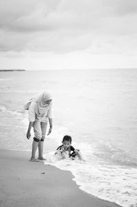 Woman and girl at beach against sky