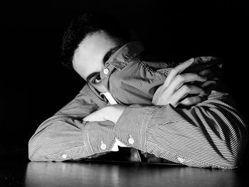 Portrait of woman sitting against black background