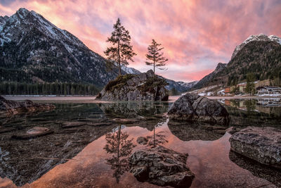 Scenic view of lake and mountains against cloudy sky during sunset