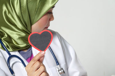 Midsection of man holding heart shape against white background