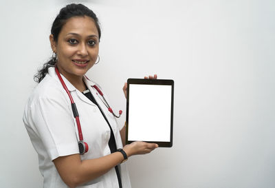 Portrait of smiling young woman standing against white background