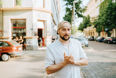 Portrait of man standing on street against buildings in city