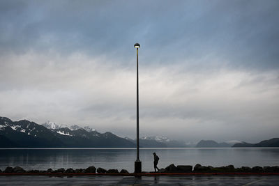 People on street by lake against sky