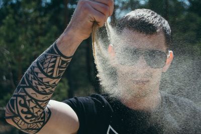 Man releasing sand with hand on sunny day