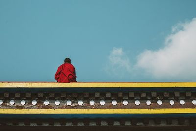 Rear view of a monk against blue sky