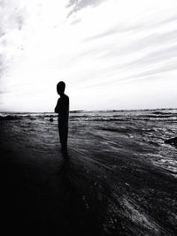 Silhouette man standing on beach against sky