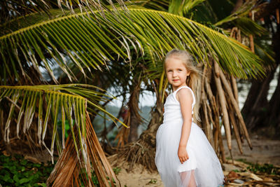 Girl standing against palm tree
