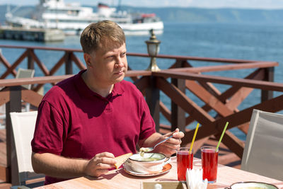 An adult blonde man has lunch on the beach in a cafe in the fresh air.