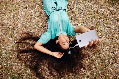High angle portrait of smiling young woman lying on field