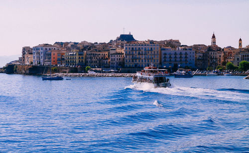 Boats sailing in sea against clear sky