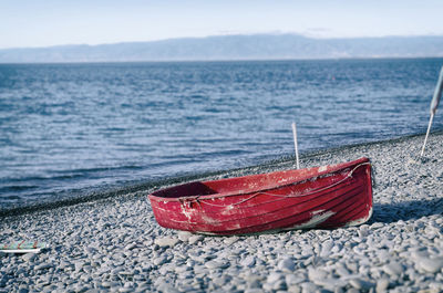 Red boat moored on pebbles shore at beach