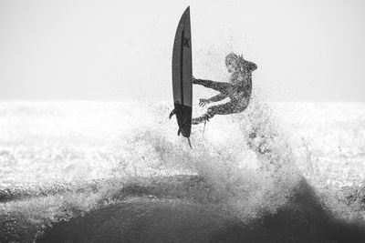 Man surfing in sea against clear sky