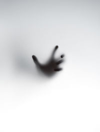 Shadow of hand on glass against white background