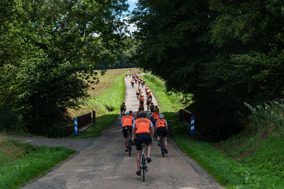 Rear view of people riding bicycle on footpath