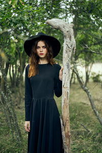 Young woman standing against tree trunk