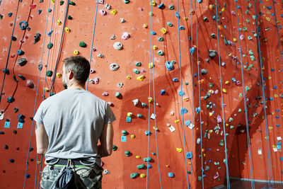 Rear view of man standing against climbing wall