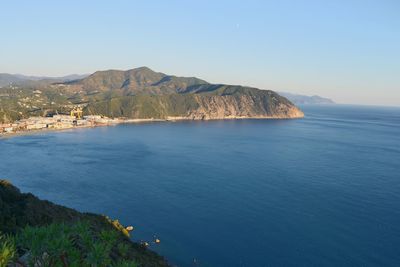 Scenic view of sea and mountains against clear blue sky