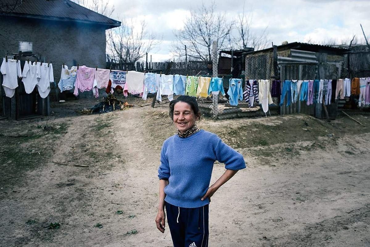 PORTRAIT OF SMILING YOUNG WOMAN HANGING ON CLOTHESLINE