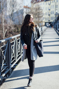 Beautiful young woman walking on footbridge during sunny day