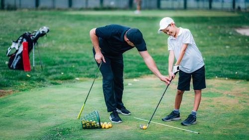 Rear view of men playing on golf course