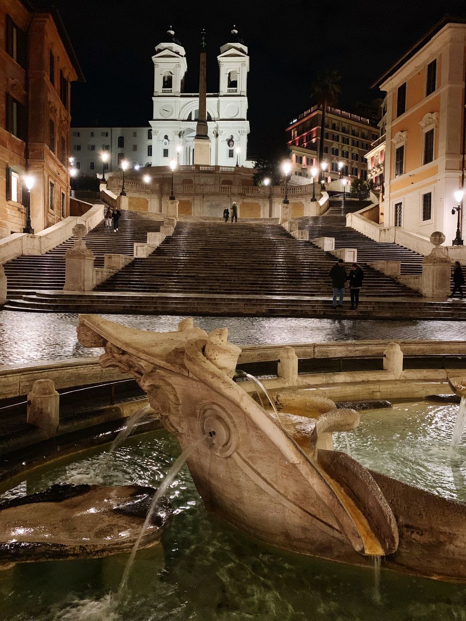 STATUE BY ILLUMINATED BUILDINGS AT NIGHT