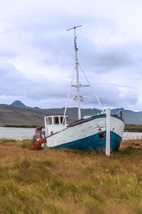 Abandoned ship on field against sky