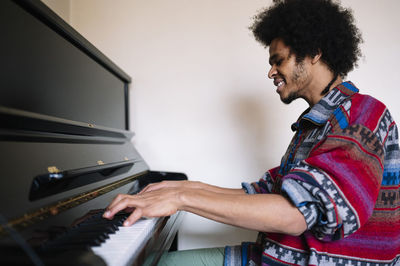 Smiling male musician practicing on piano in living room