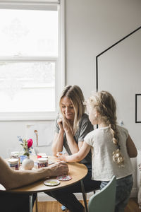 Woman and girl sitting on table at home