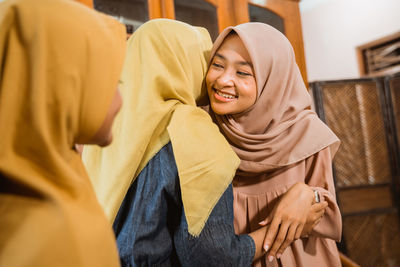 Smiling young females greeting at home