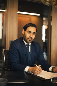 Portrait of confident lawyer analyzing documents at table in legal office