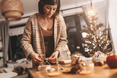 Good mood woman in a cozy environment wrapping gifts for christmas, stylish decoration, vintage